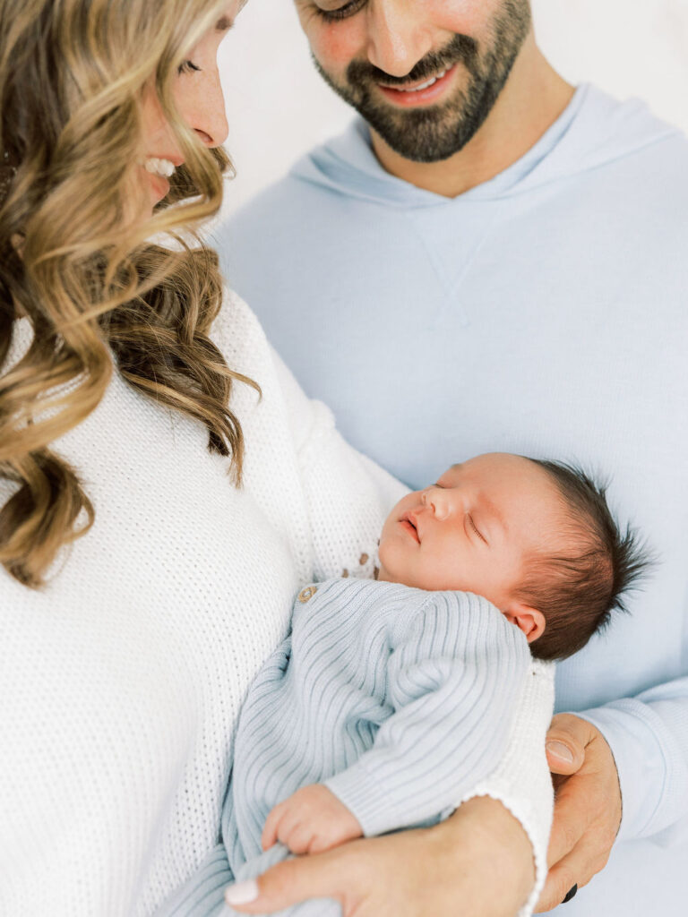 Mom and dad looking down at their sleeping newborn during a relaxed newborn photography session