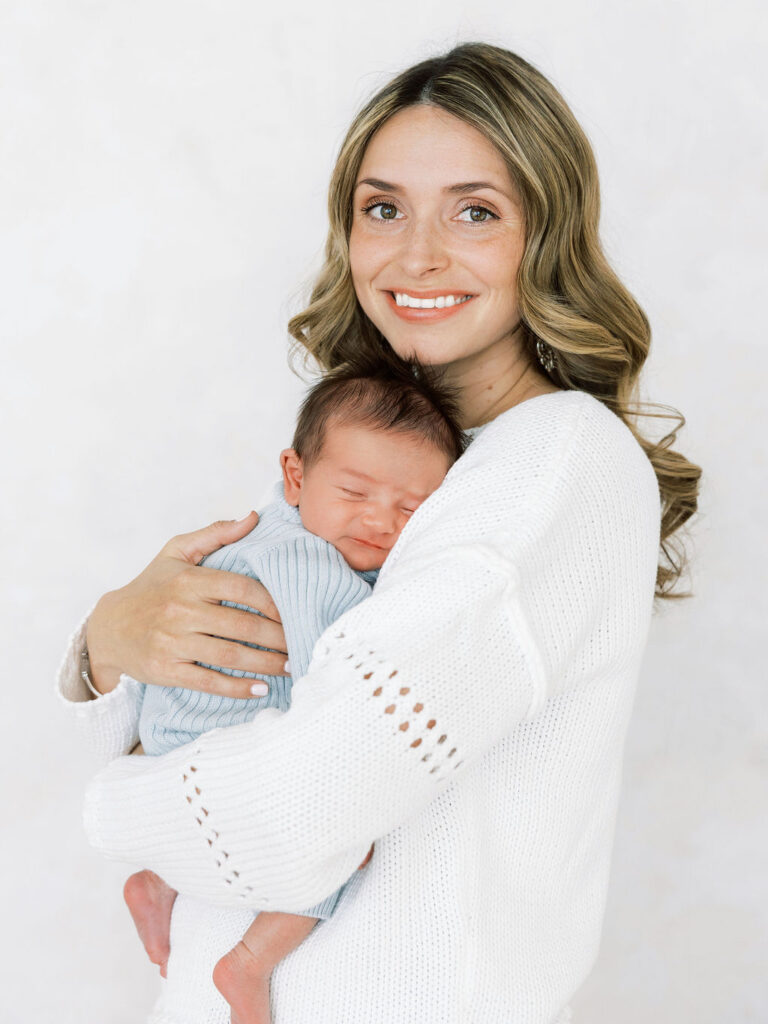 Mom smiling while holding her sleeping newborn baby during a studio newborn photography session