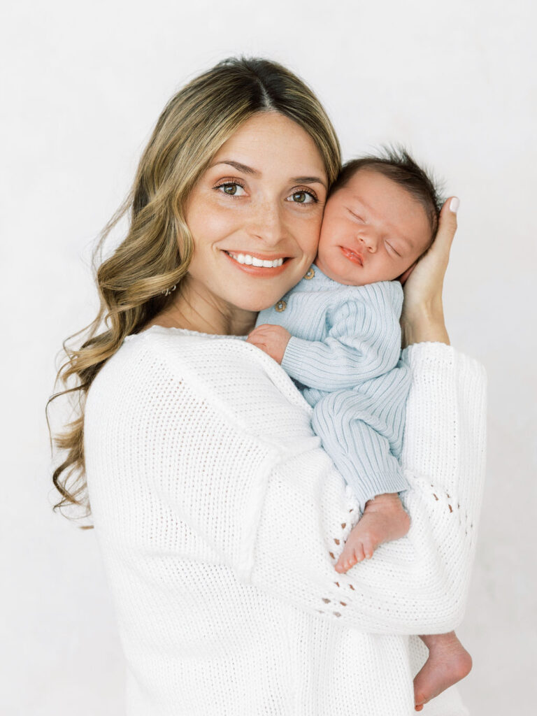 Mother holding her sleeping newborn close during a soft and natural studio session