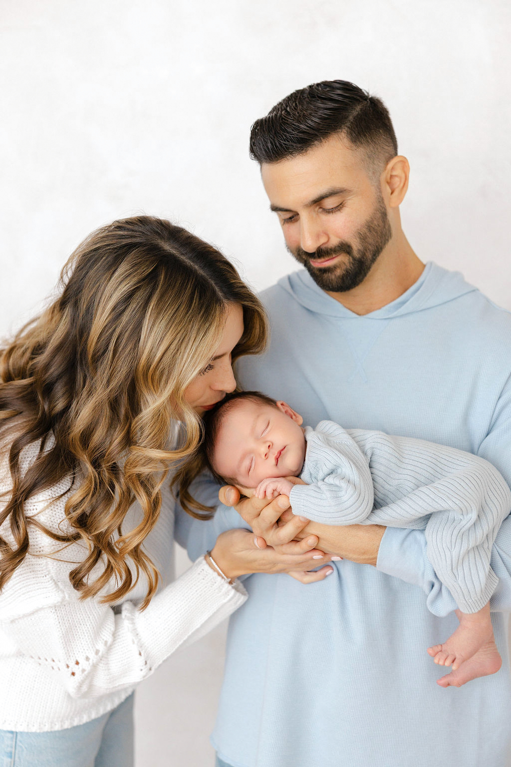 Mother kissing her newborn baby during a lifestyle studio newborn session in Santa Clarita