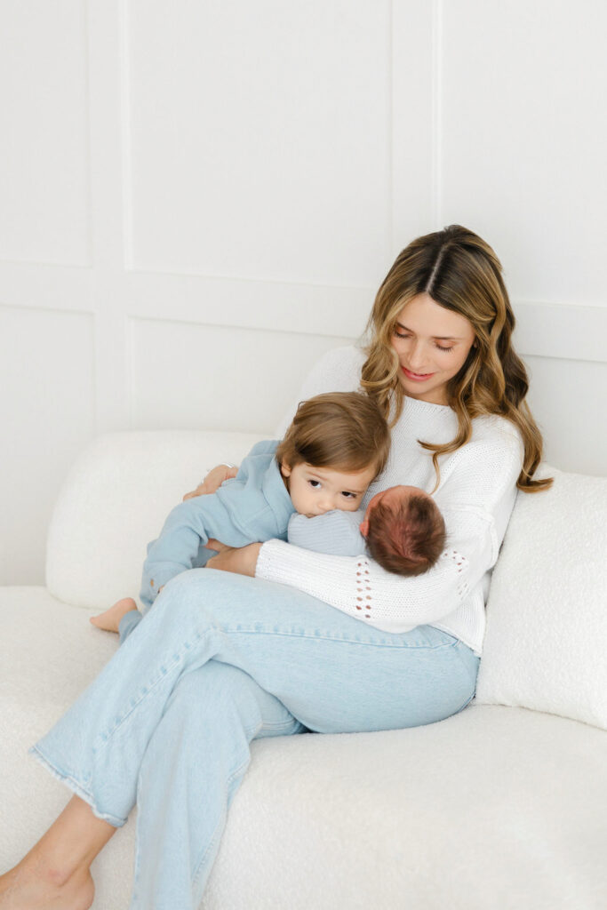 Mother snuggling her newborn and toddler during a relaxed lifestyle newborn session