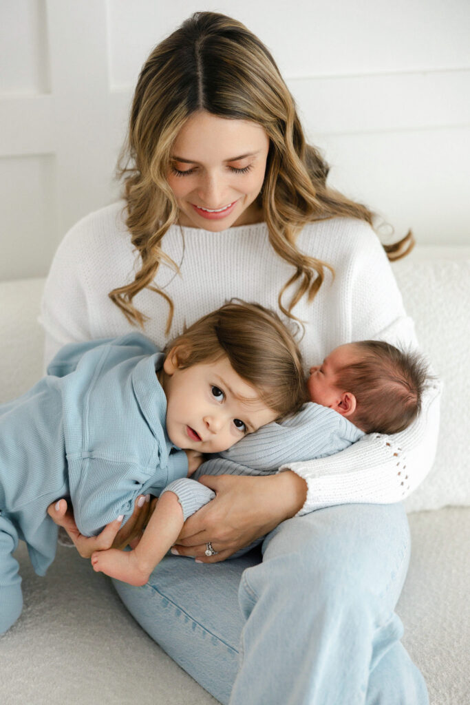 Mom holding her newborn baby while an older sibling cuddles close during a Santa Clarita newborn photography session