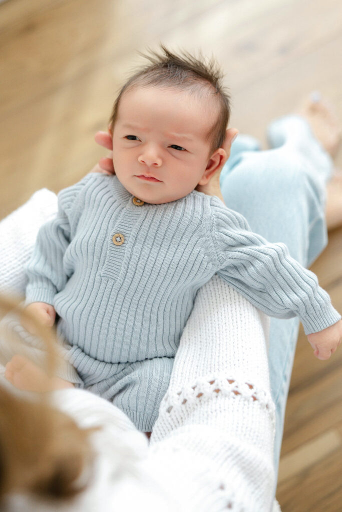 Awake newborn baby resting comfortably in mom’s arms during a lifestyle newborn photography session