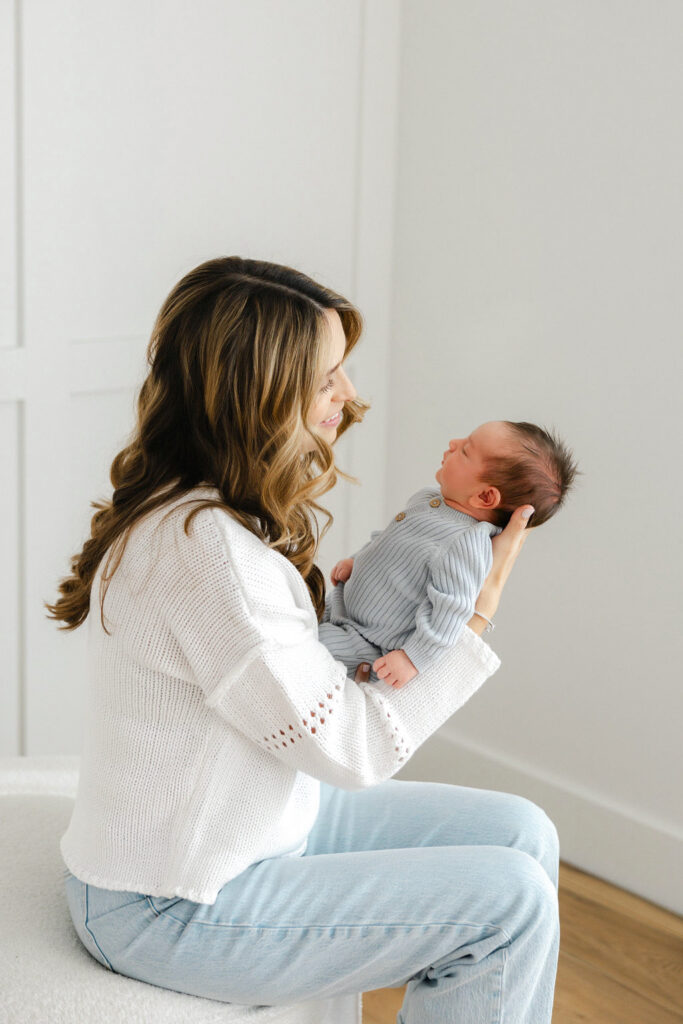 Mom looking lovingly at her newborn baby during a relaxed studio newborn photography session