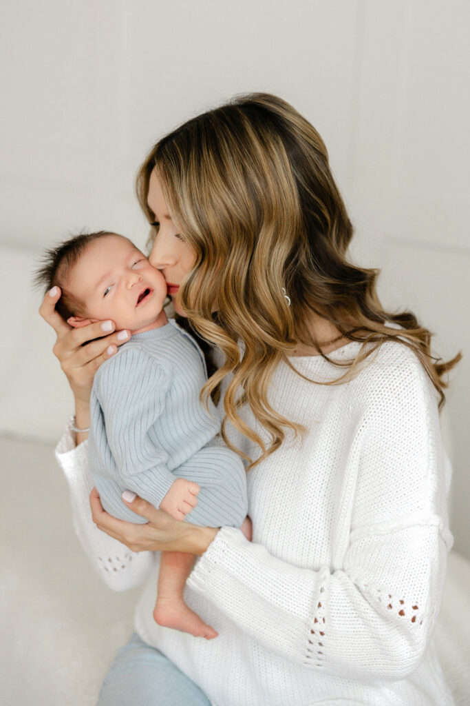 Mom kissing her newborn baby during a relaxed Santa Clarita studio newborn photography session.