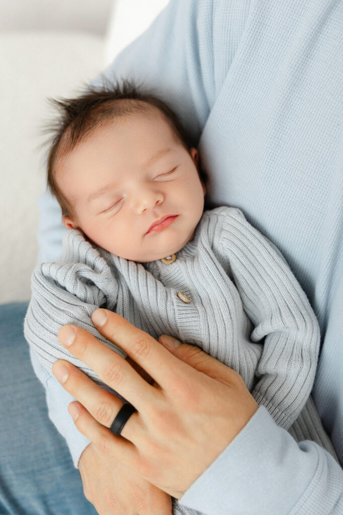 Sleeping newborn baby wearing a blue sweater during a studio session