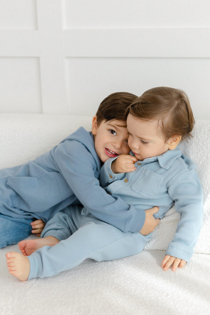 Two older brothers cuddling together during a relaxed studio newborn family session.