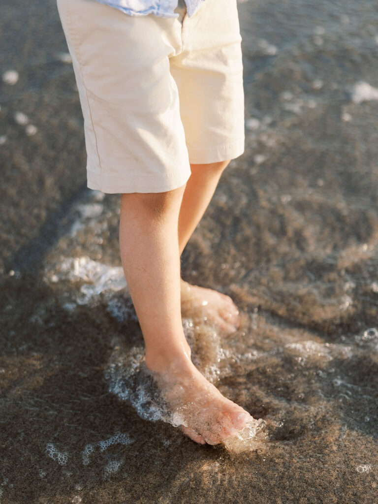 Child standing barefoot in the ocean during a Ventura beach family photo session