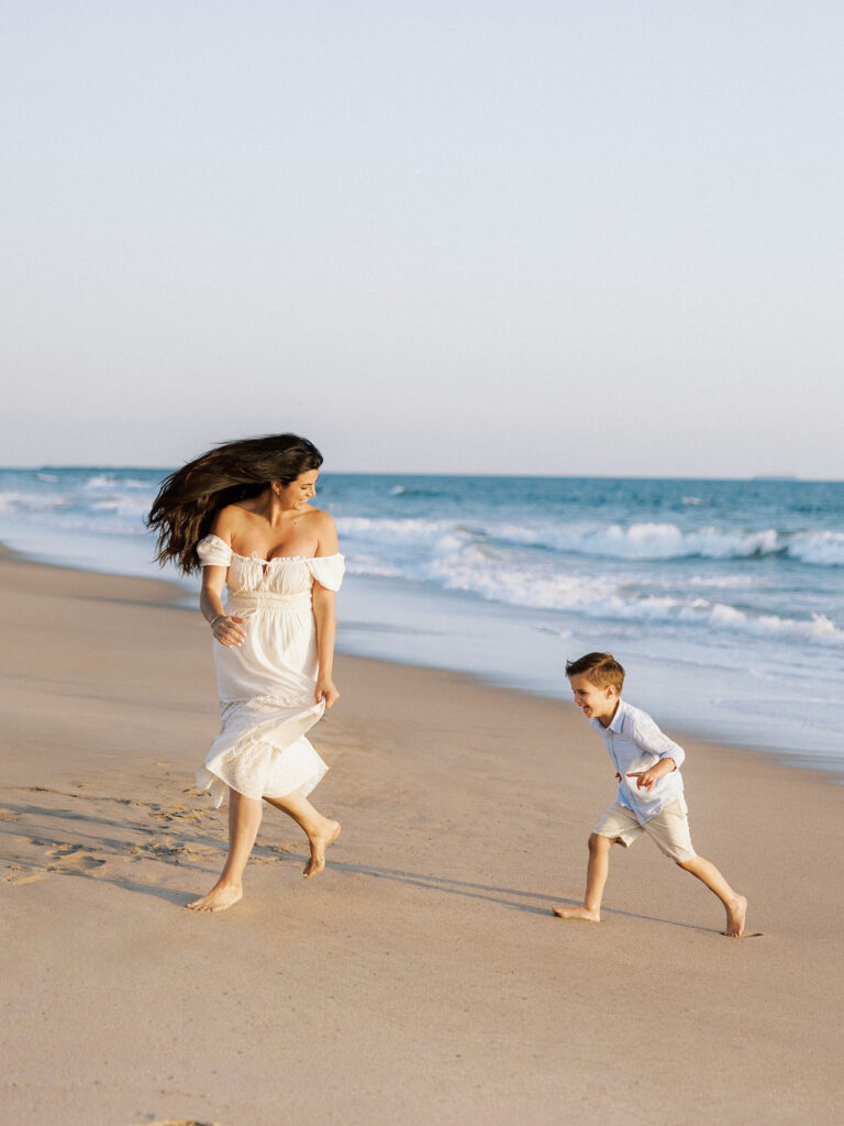 Mom and son running together on the beach during a Ventura family photo session