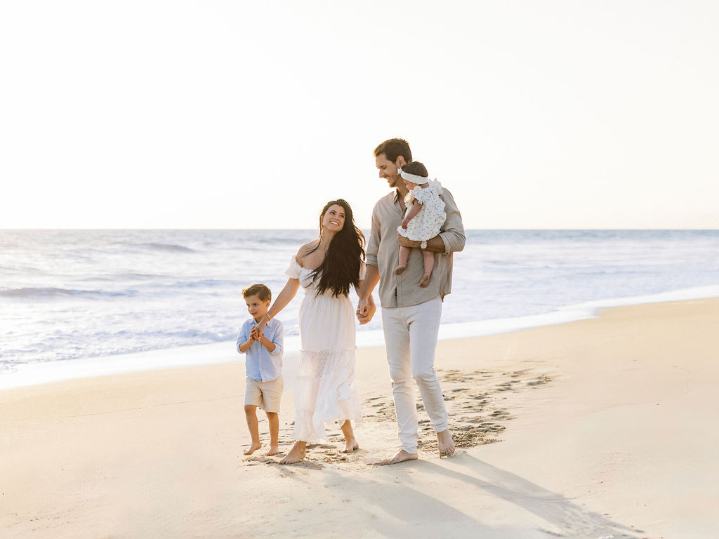 Family walking on Oxnard Beach in Ventura wearing coordinated neutral outfits
