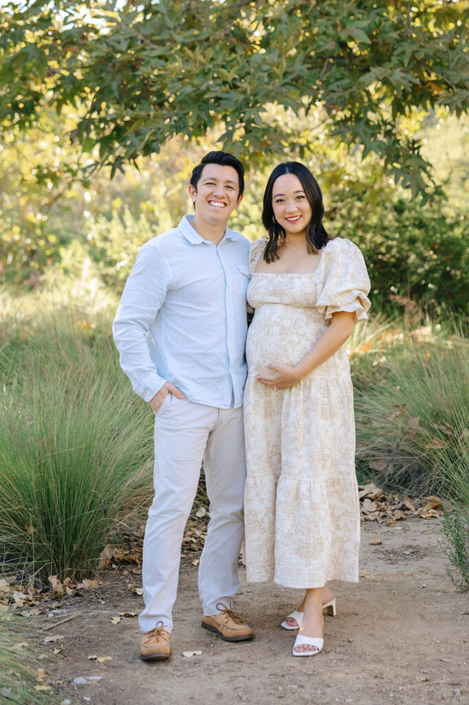 Pregnant couple smiling together in soft neutral clothing for maternity photo outfit inspiration