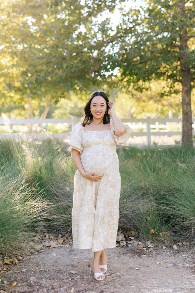 Pregnant woman smiling in a romantic dress showing what to wear for maternity photos