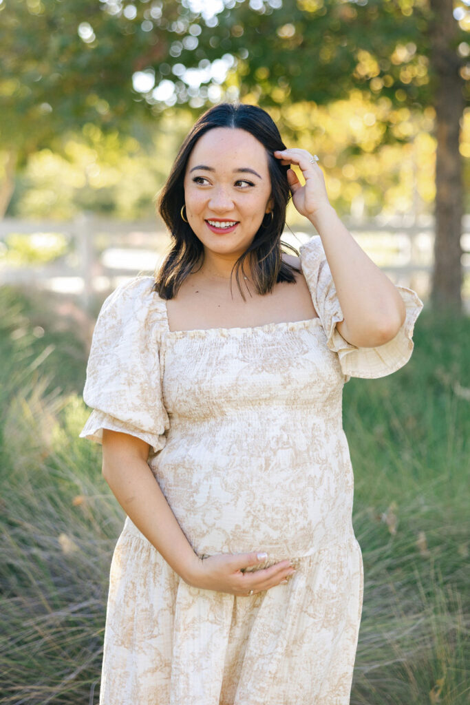 Pregnant woman smiling in a romantic dress showing what to wear for maternity photos