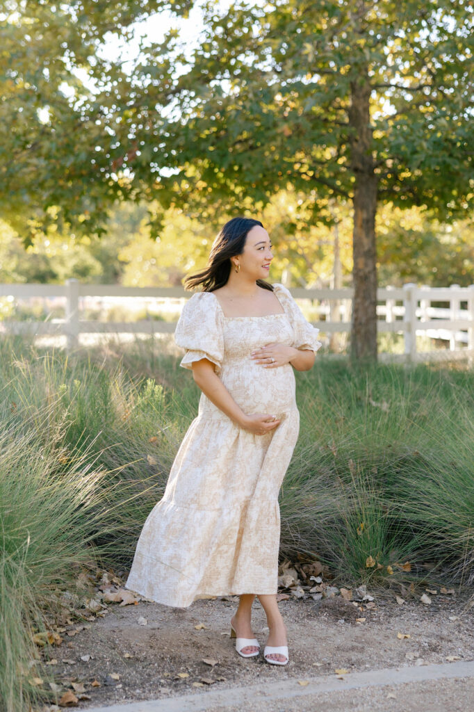 Expecting mom posing in a feminine floral dress during a relaxed outdoor maternity session