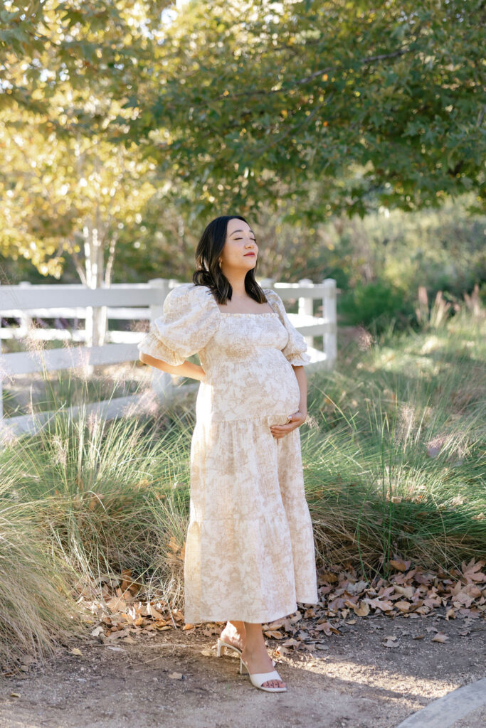 Pregnant woman walking outdoors in a romantic floral dress during a Santa Clarita maternity session