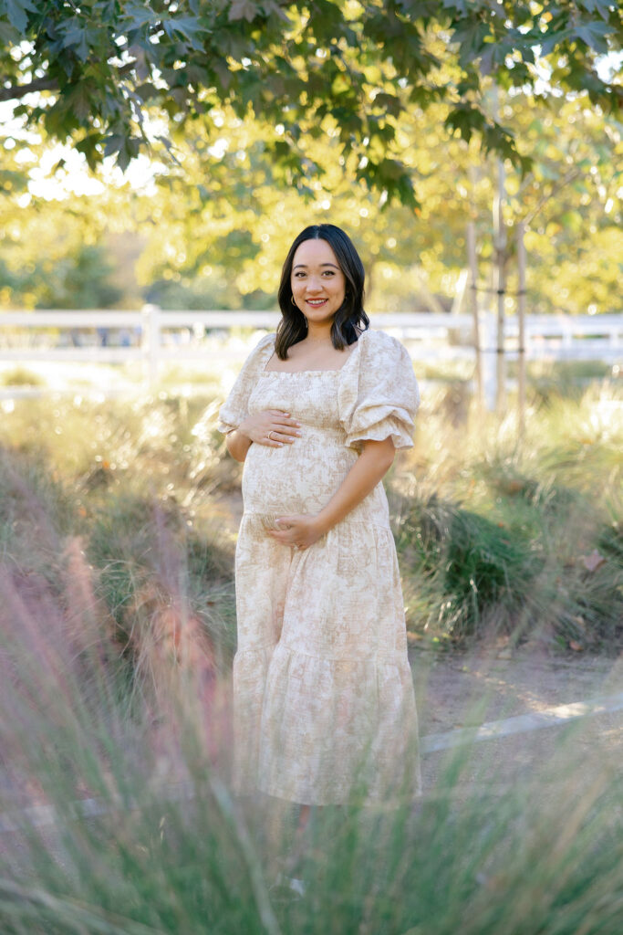 Pregnant mom in a soft floral dress showing what to wear for maternity photos outdoors