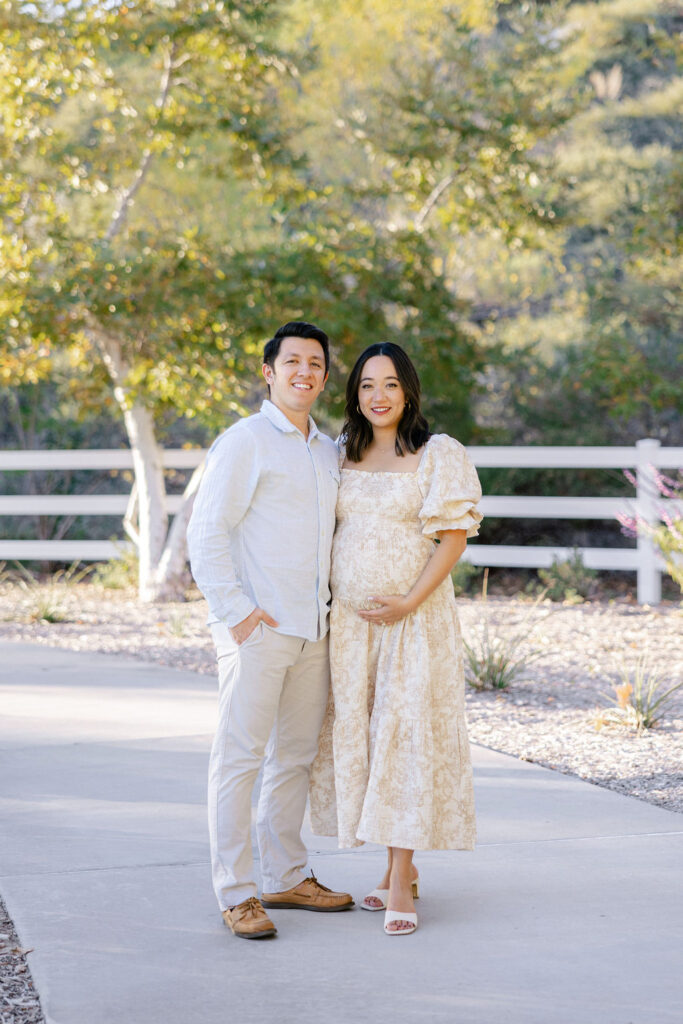 Expecting couple wearing coordinated neutral outfits during an outdoor maternity photo session