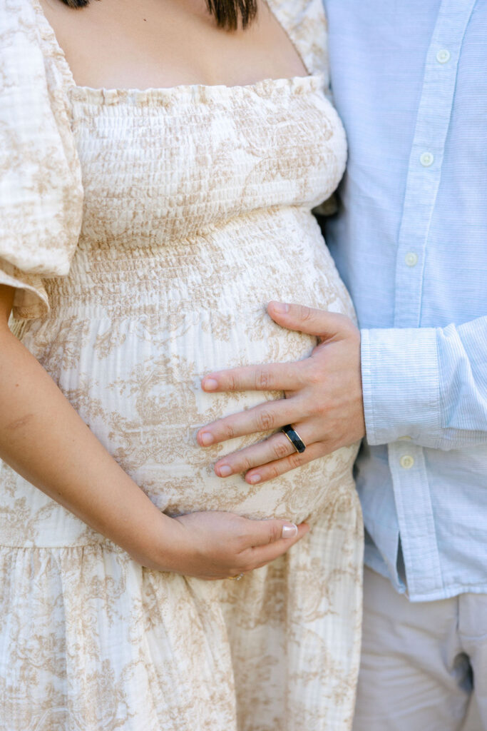 Close up of an expecting couple highlighting coordinated neutral outfits for maternity photos