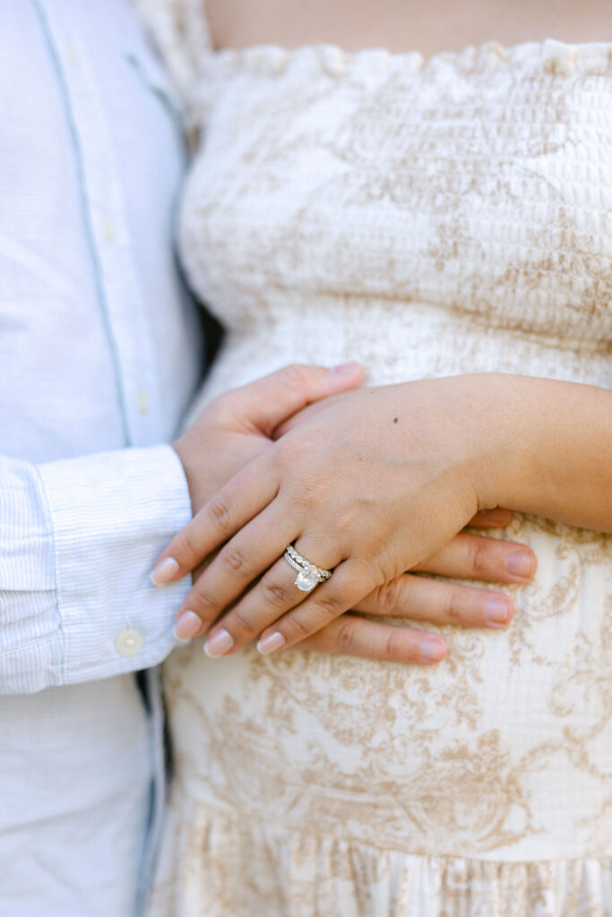 Close up of a pregnant belly with a soft neutral cardigan for maternity outfit inspiration
