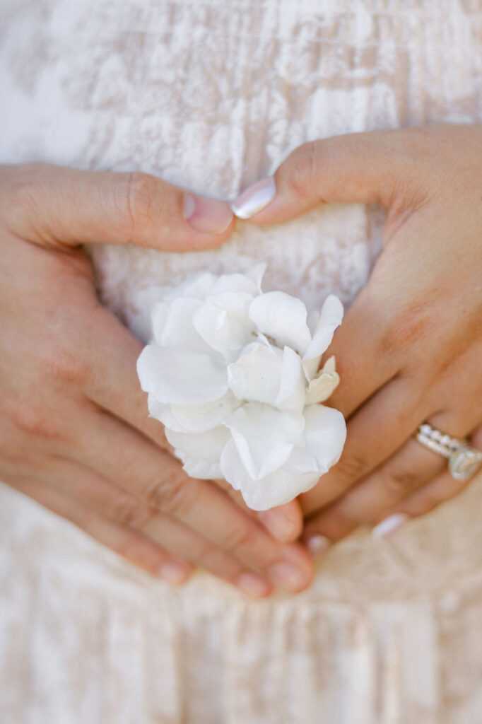Close up of an expecting couple forming a heart with their hands over the baby bump during a maternity photo session.