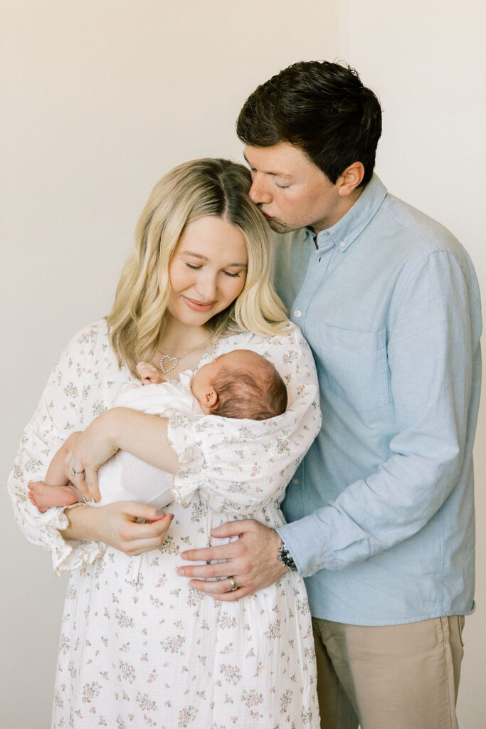 Parents cuddling their newborn in soft blue and floral tones, a coordinated outfit idea for newborn family photos