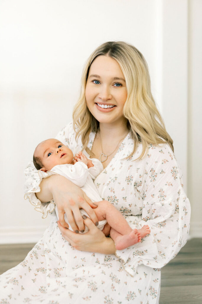 Mom holding her newborn while wearing a soft floral dress, a beautiful example of light neutral styling for newborn photos