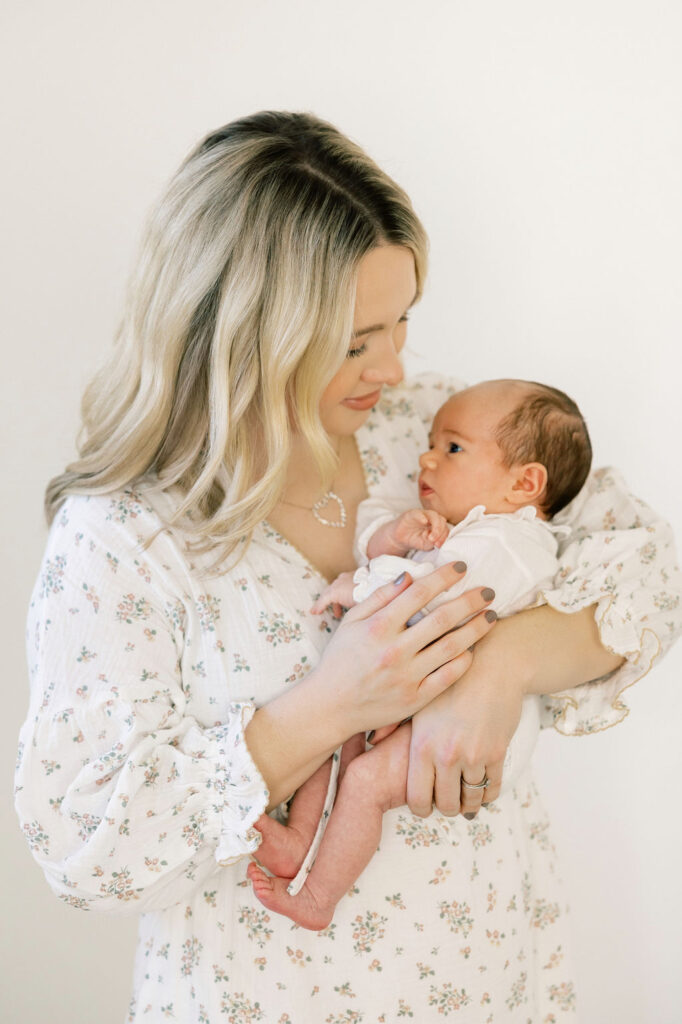 Mom holding her newborn in a soft floral dress, a light and timeless outfit idea for newborn photos