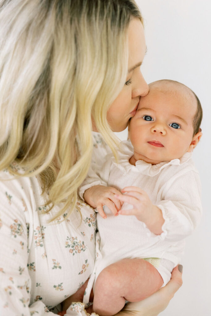 Mom cuddling and kissing her newborn during an in home newborn session