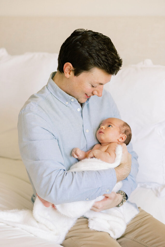 Dad looking at his newborn during an intimate in home family photo session