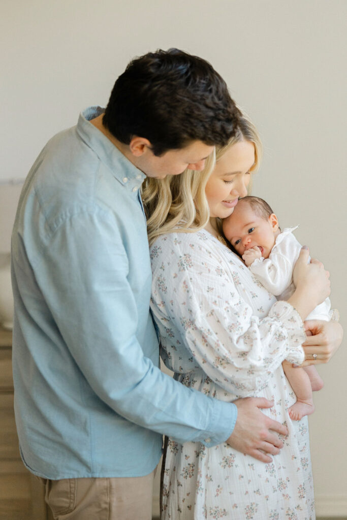 Family wearing soft neutral outfits for an in home newborn photography session