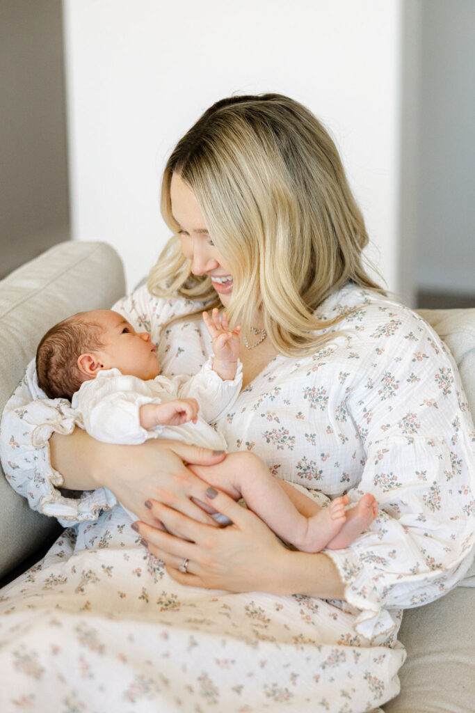 Mom holding her newborn baby in a soft neutral outfit for family photos