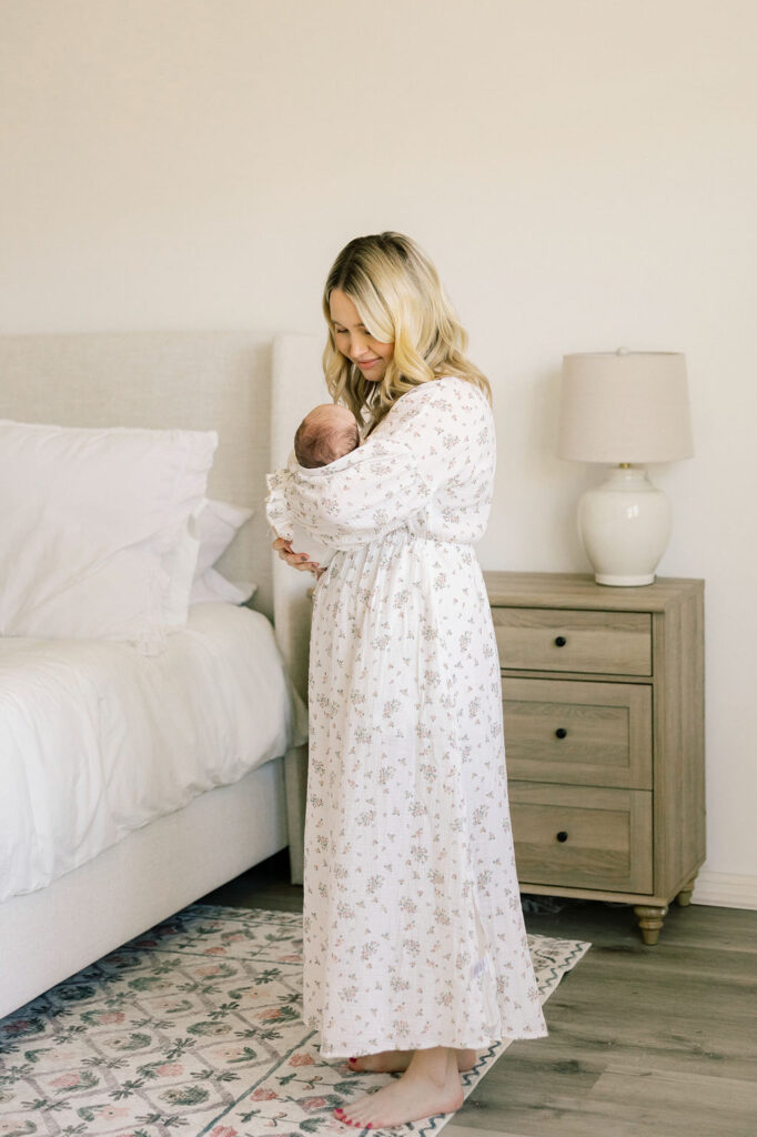 Mother holding her baby in a bright neutral home during newborn photos