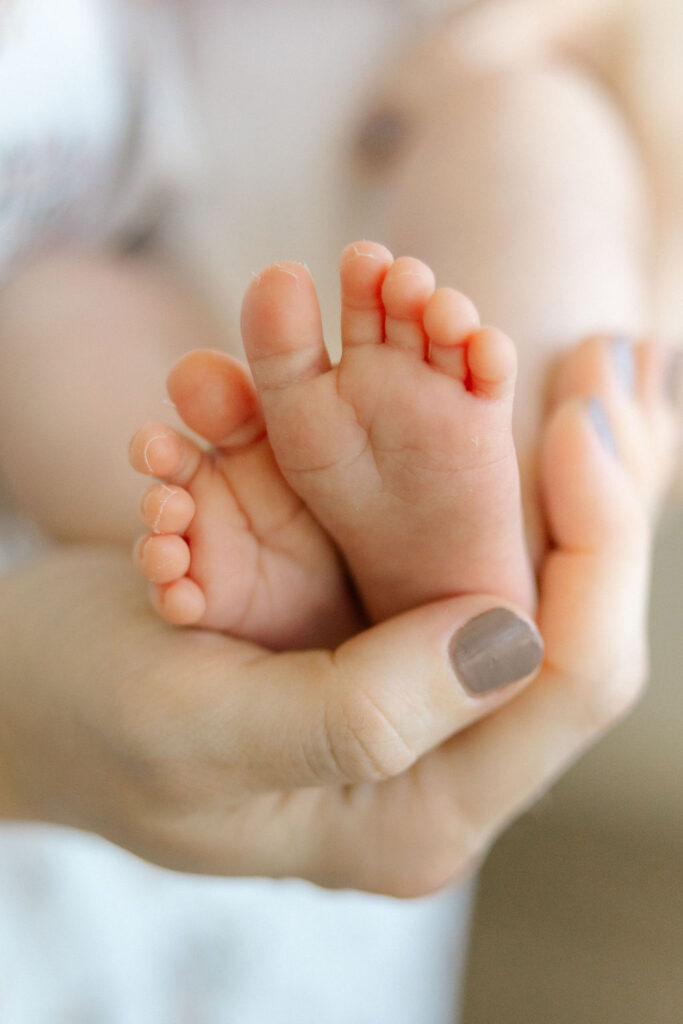 Close up of newborn baby feet held gently in a parent’s hand during a natural Santa Clarita newborn photography session