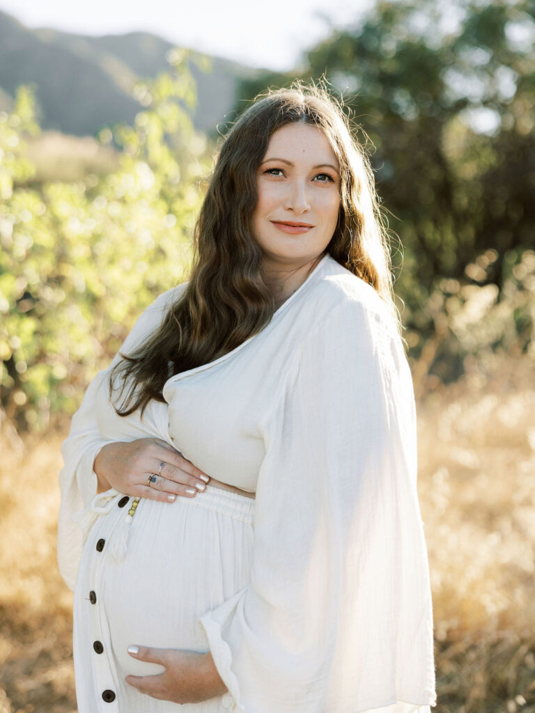 Pregnant woman cradling her baby bump during a soft golden hour maternity session in Santa Clarita