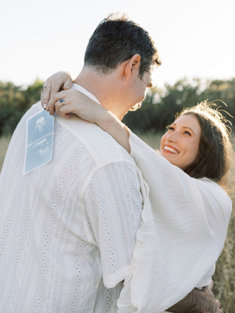 Expecting couple embracing with an ultrasound photo during a golden hour maternity session in Santa Clarita