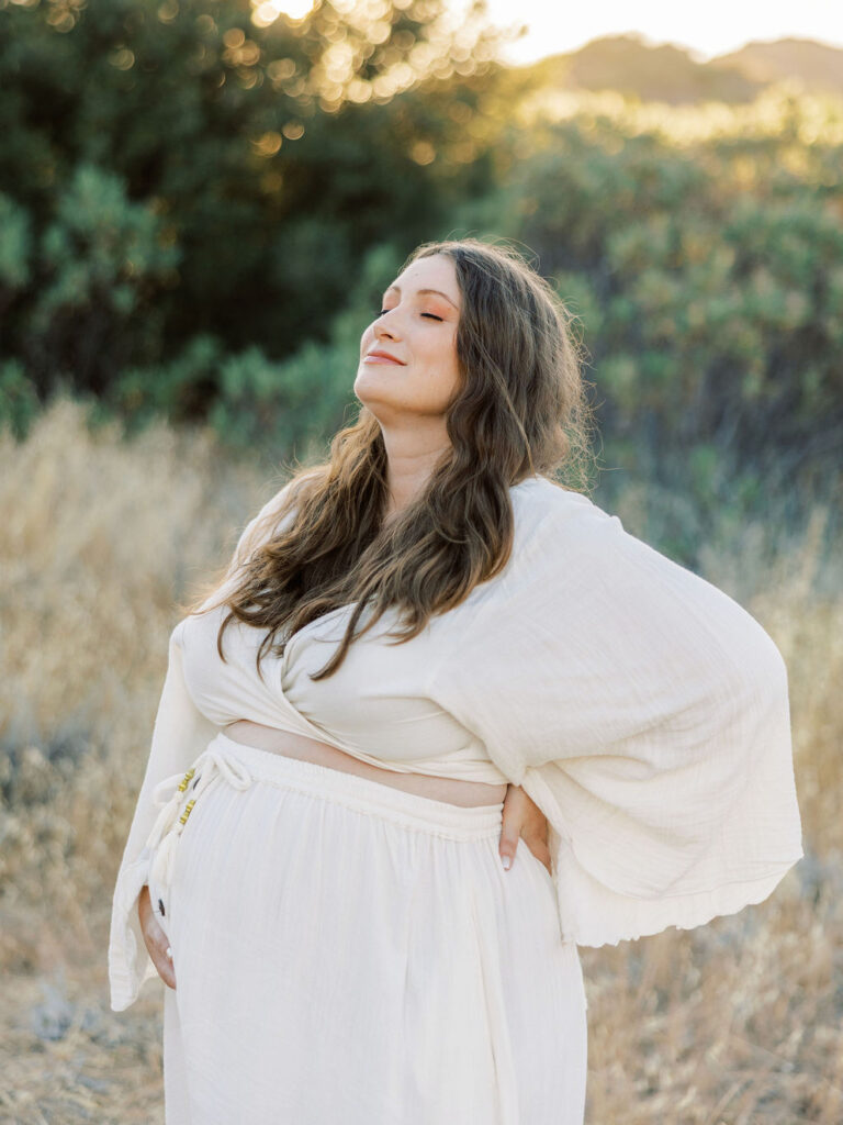 Pregnant woman posing in a white dress during a golden hour maternity session in Santa Clarita