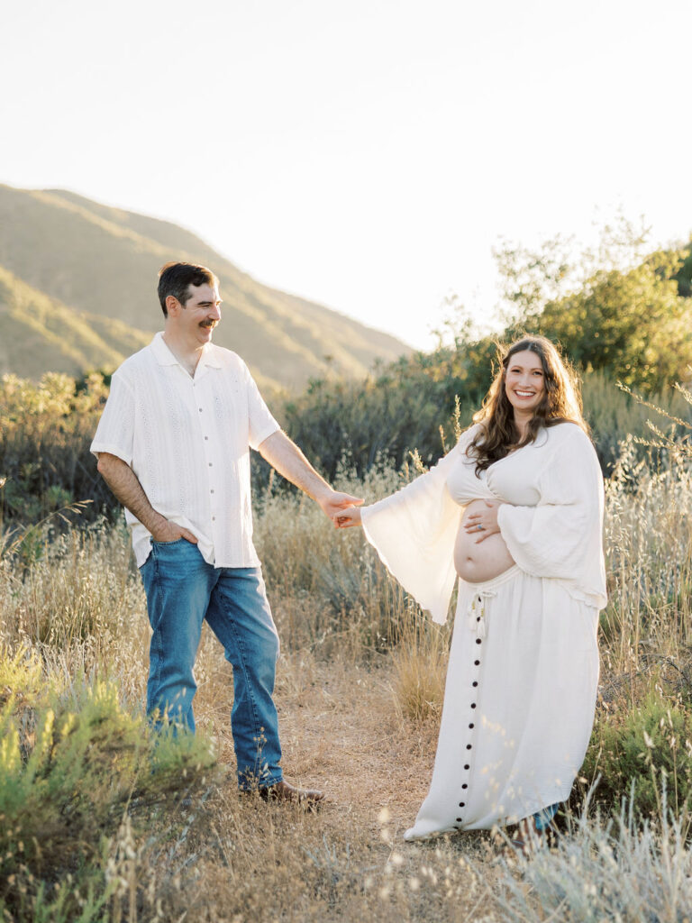 When to Take Maternity Photos with an expecting couple holding hands during a golden hour Santa Clarita maternity session