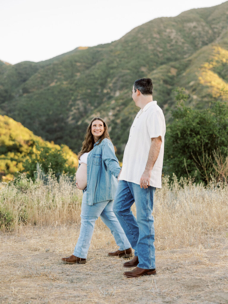 Expecting couple holding hands while walking during an outdoor maternity session in Santa Clarita