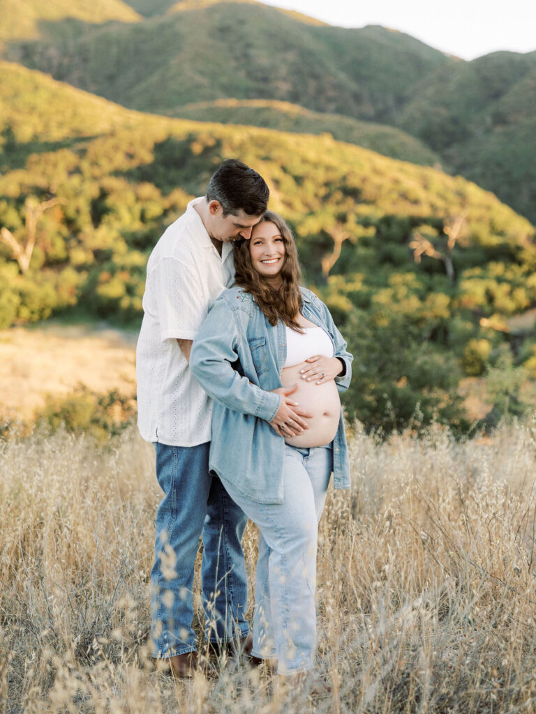 Expecting couple embracing during a romantic outdoor maternity photo session