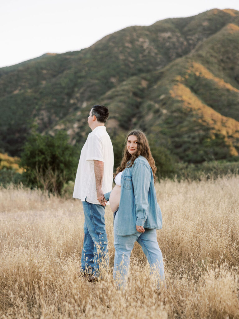 Pregnant couple walking together with scenic Santa Clarita hills behind them