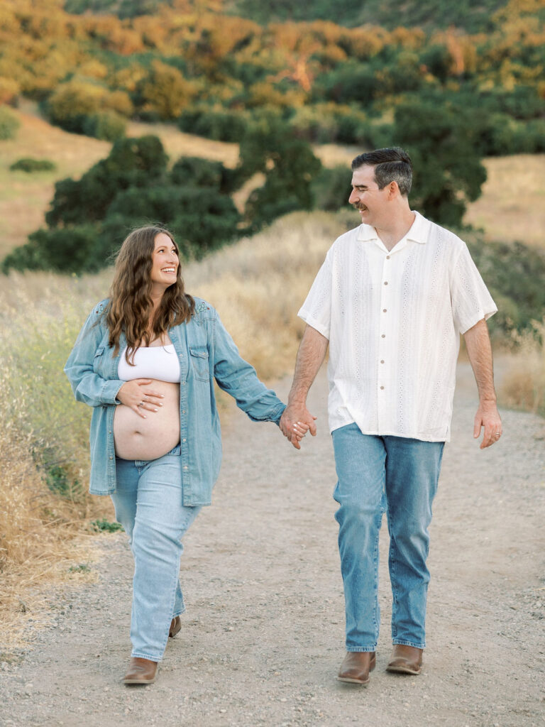 Pregnant couple walking together with rolling hills in the background