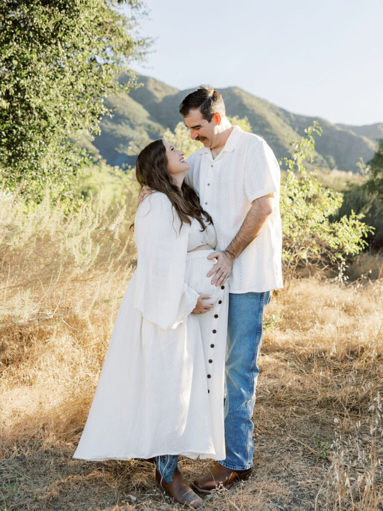 Expecting couple standing together in a sunlit Santa Clarita field