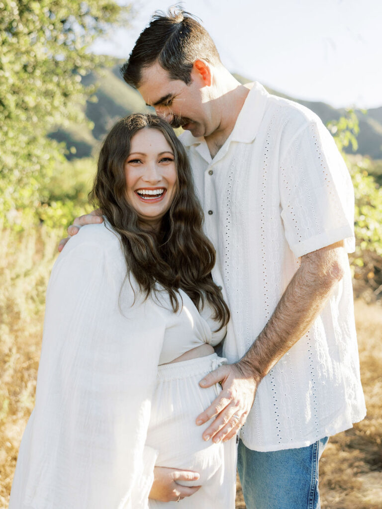 Pregnant woman smiling with her partner during an outdoor maternity session