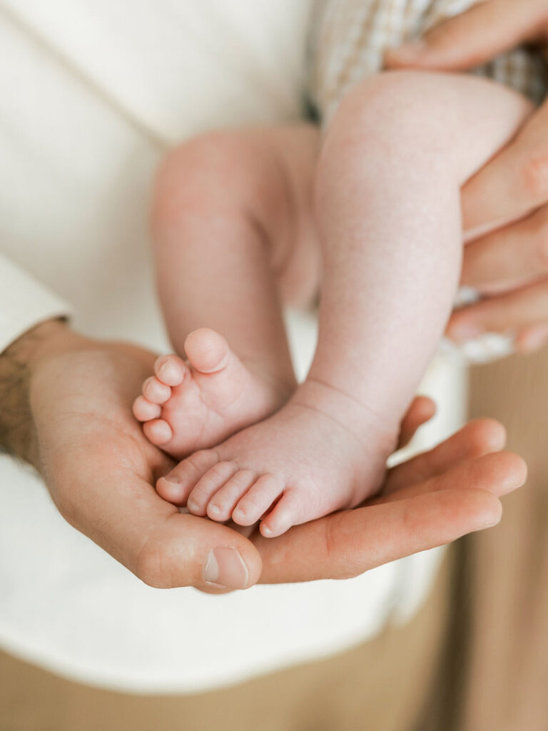 Close up of newborn baby resting in a parent’s hands during a studio newborn session