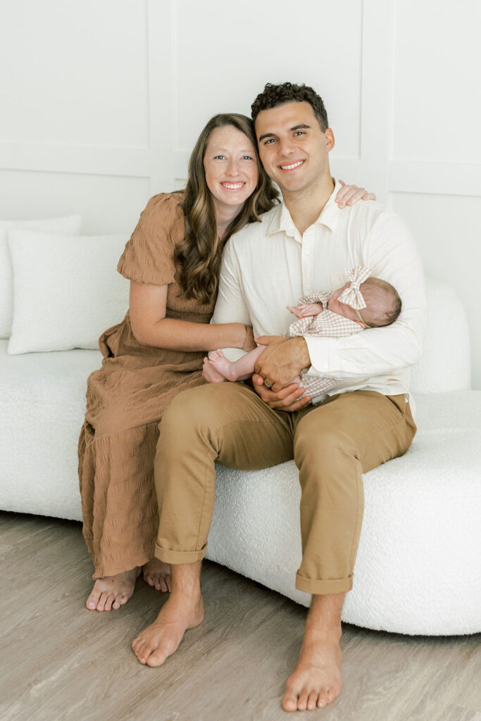 Mom and dad seated together with their newborn baby during a Santa Clarita newborn photography session