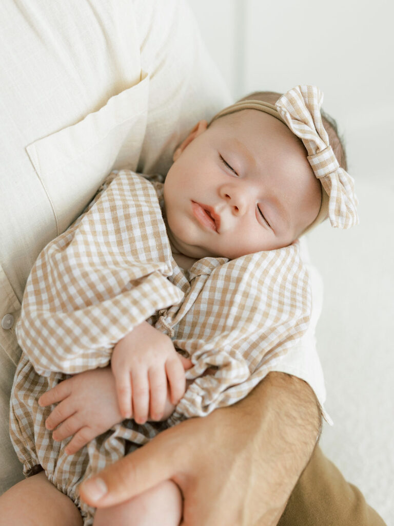 Newborn baby resting comfortably in a parent’s arms during a studio newborn session