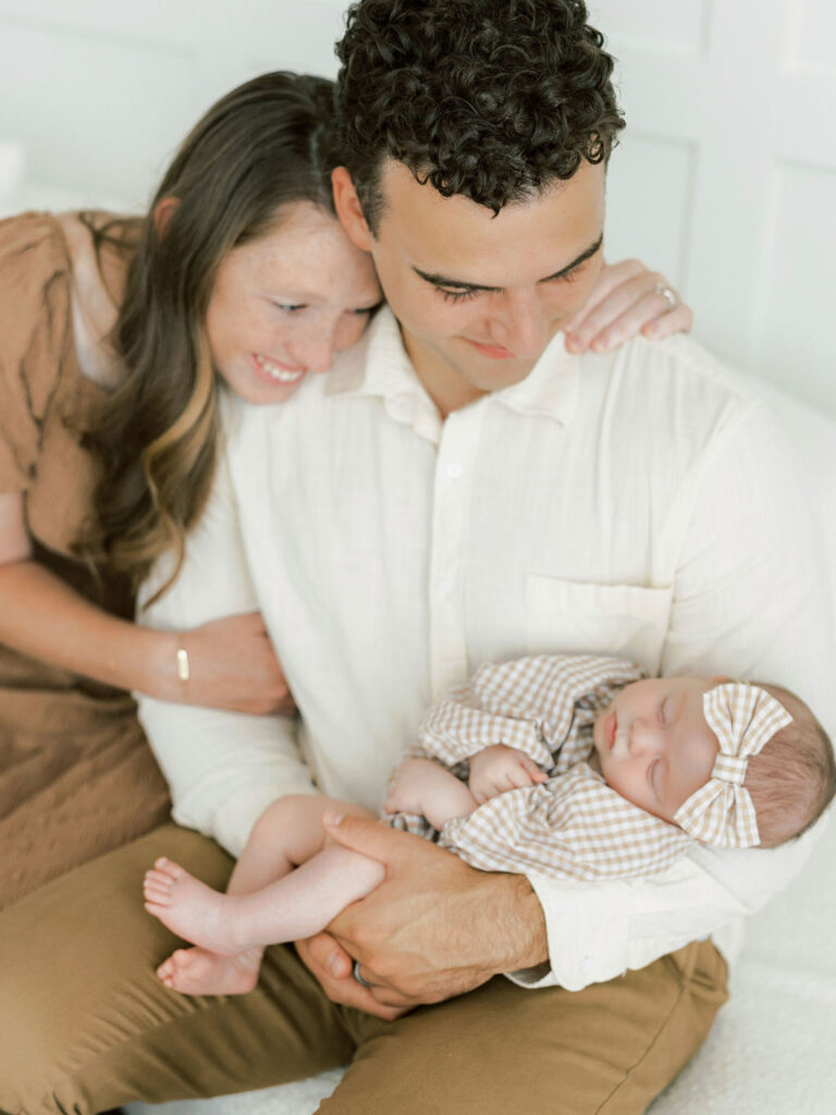 Parents looking down at their newborn baby while preparing for newborn photos