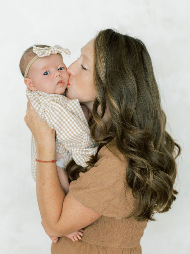 Mom cuddling her newborn baby close during studio newborn photos
