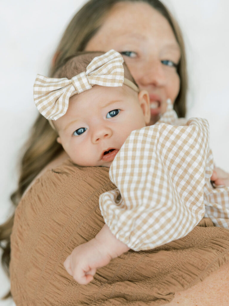 Mom smiling while holding her newborn baby during a relaxed newborn photography session in Santa Clarita
