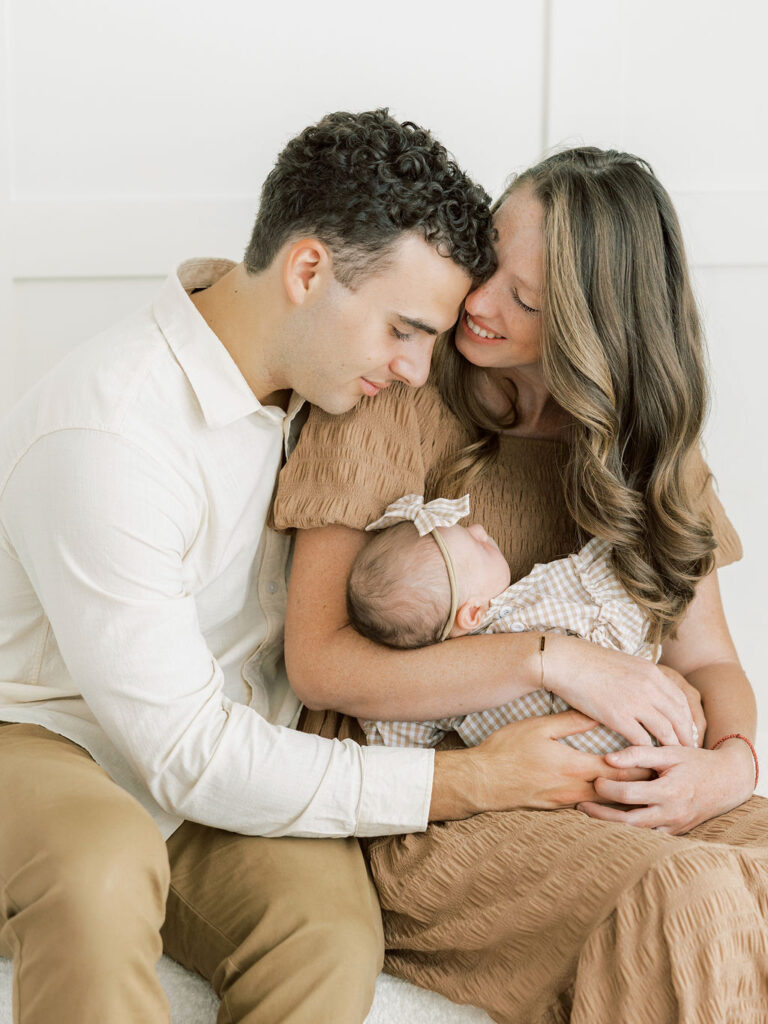 Parents sharing a quiet moment while holding their newborn baby during studio newborn photos